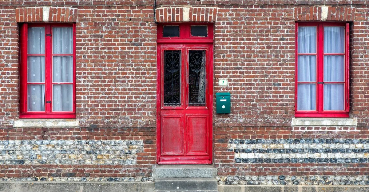 Porte et fenêtres rouges sur une façade en brique vintage, mettant en valeur l'architecture traditionnelle.