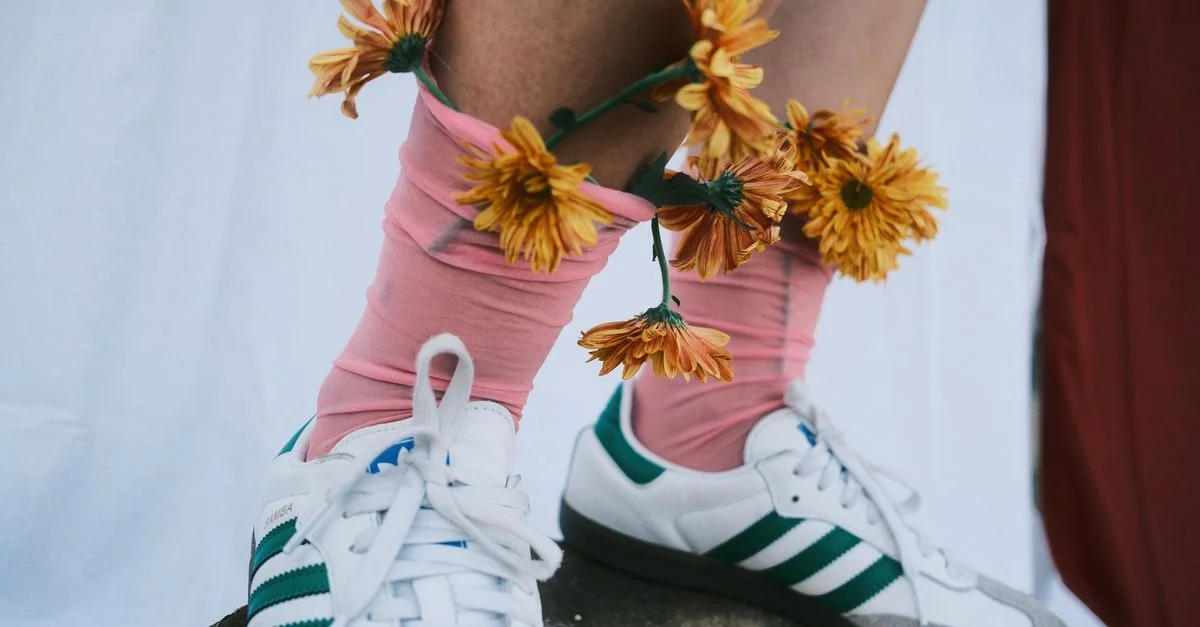 Gros plan artistique de jambes ornées de fleurs et de baskets pour un look unique.